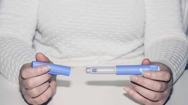 Insulin injection pen or insulin cartridge pen for diabetics. Medical equipment for diabetes parients. Woman holding an injection pen for diabetic.