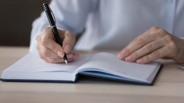 mature person journaling with pen