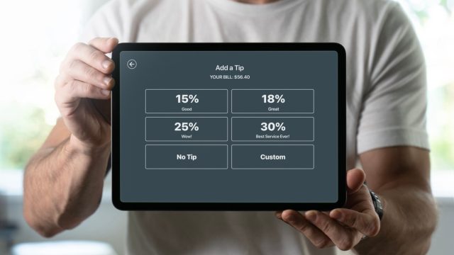 man holding tablet with tipping screen
