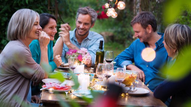 Group of middle aged friends at outdoor dinner party laughing