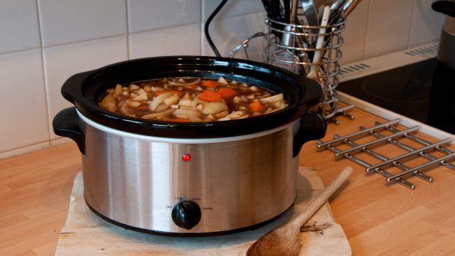 Slow cooker with vegetables inside sitting on a kitchen counter