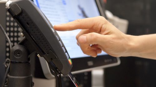 Close up of person hand inserting a credit card in the terminal and entering the pin code. Equipment for paying with bank cards without the use of cash. Payment through the terminal of purchases.