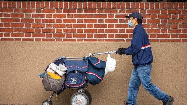 San Francisco, USA - April 4, 2020: San Francisco postal worker in mask delivering mail during stay-at-home order.