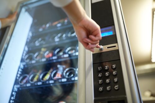 hand pushing a button on a vending machine