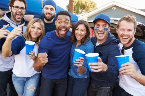 Group Of Sports Fans Tailgating In Stadium Parking Lot