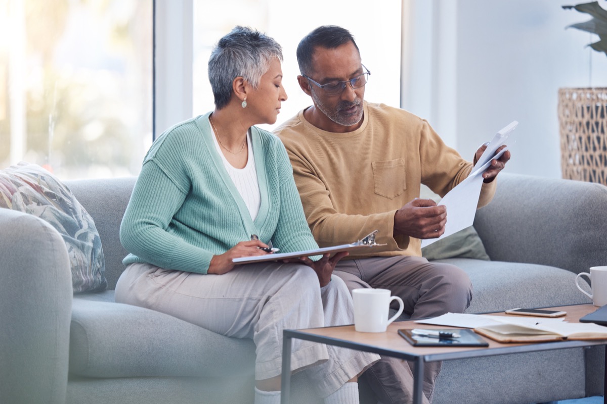 Mature couple sitting on couch going over paperwork