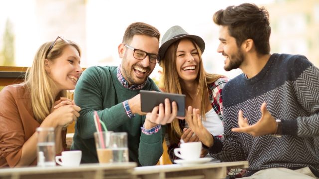group of friends laughing and using their tablet to look up funny puns