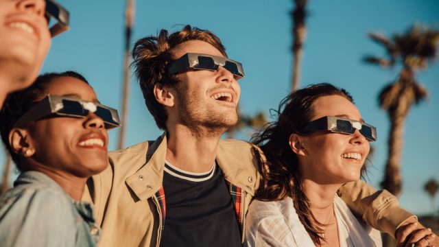 A group of people watching a solar eclipse while wearing protective glasses