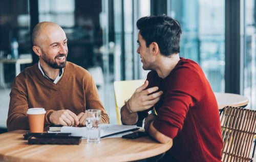 two men having a conversation at a cafe