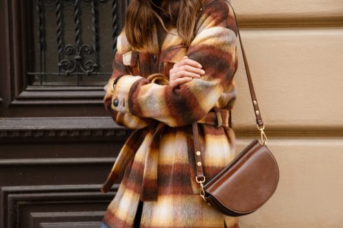 Street style concept with woman wearing plaid flannel wool jacket and brown purse