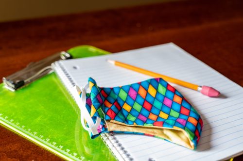 fabric face mask on top of school supplies