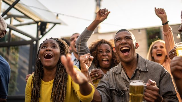 A group of fans in a bar watching a sporting event or football