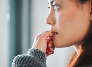 Close up of a woman biting her nails and looking anxious