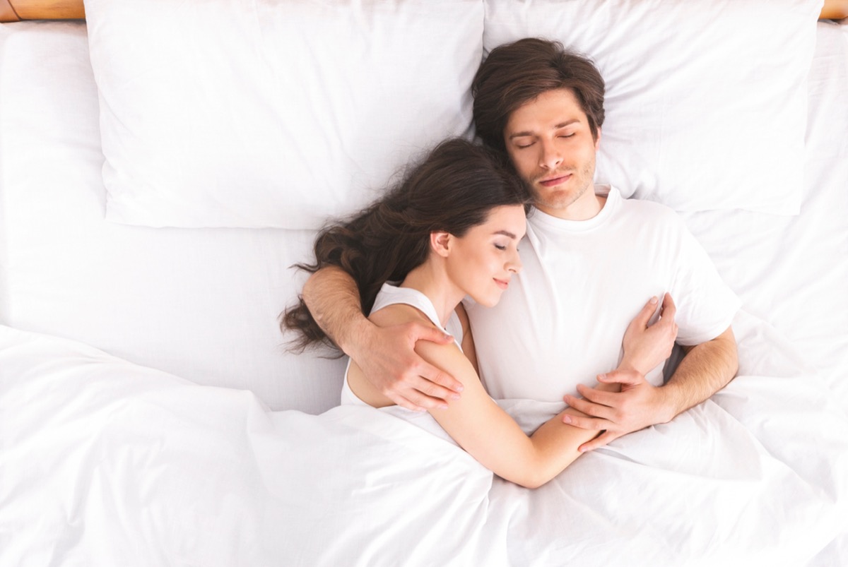man and woman cuddling in bed