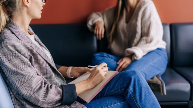 The psychologist makes a social survey of the reference group. A professional is talking to a client. Informal communication at the interview, business consultant writes notes in a notebook.