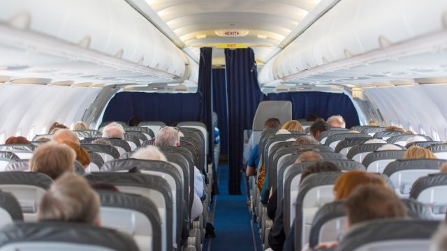 A view of a commercial airline cabin filled with seated passengers.