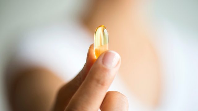 Woman holding omega 3 capsule.
