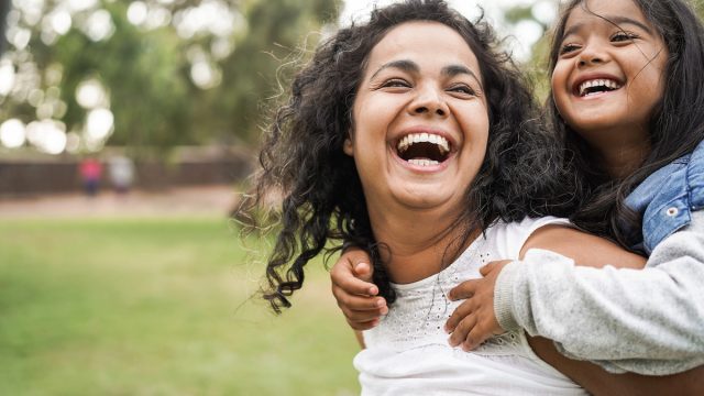 Happy mother and daughter playing outside and laughing