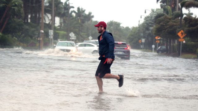 Storm Nicole nears hurricane strength as a man jogs through flooded roads in the Palm Beach area.