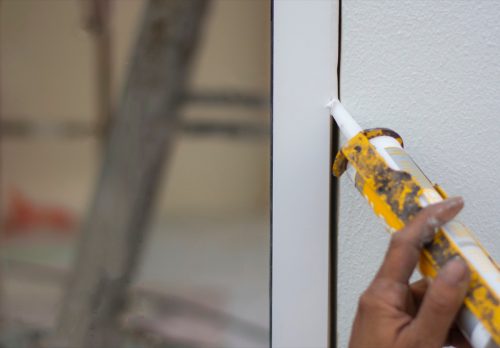 Repairman’s hand installing the windows with gun silicone. closeup