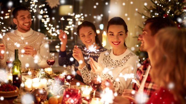 winter holidays and people concept - happy friends with sparklers celebrating christmas at home feast over snow