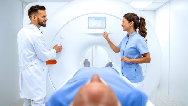 Doctors preparing patient for full body scanning procedure inside MRI diagnostic center.