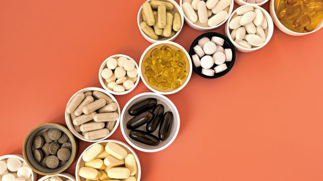 close-up of multivitamin biologically active supplements on coral background. mental wellbeing and personal health concept