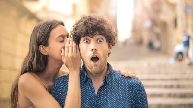 woman whispering dirty pick up lines to a man on the street