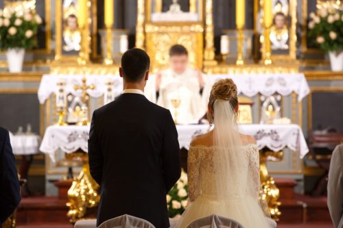Backs of bride and groom in Catholic church during wedding ceremony