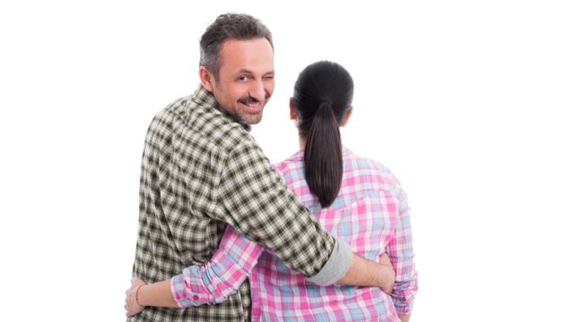 man walking arm in arm with woman winking at the camera