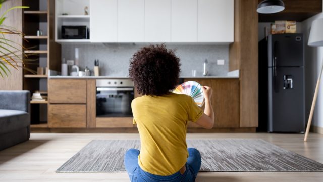 Casual woman at home choosing a color to paint the walls from a color swatch - home decor concepts