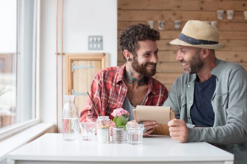 two men sitting at a cafe together