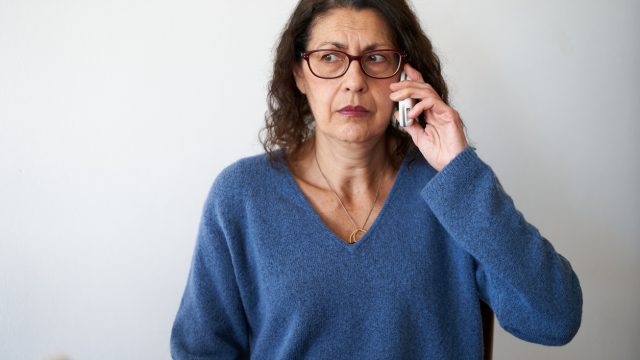 A senior woman on the phone with a suspicious or concerned look on her face