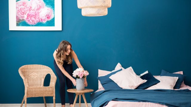 Young woman decorating bedroom with flowers at home.