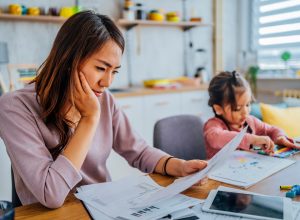 A woman looking anxiously at financial records while sitting next to a young girl