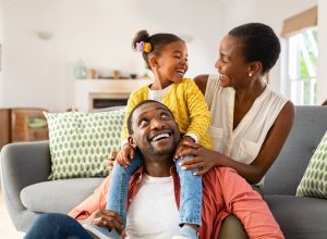 Mother, father, and small daughter laughing and playing in living room