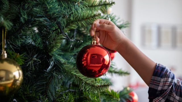 close-up of someone hanging an ornament on a christmas tree