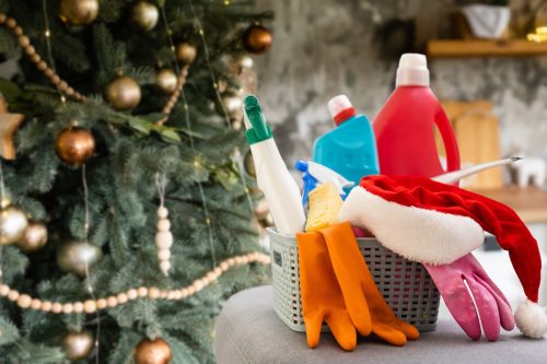 Basket of cleaning supplies sitting in front of a Christmas tree.