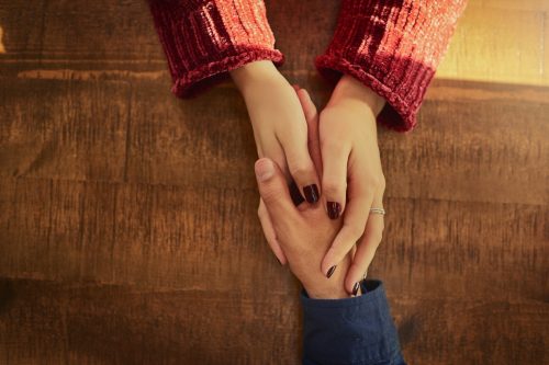 Cropped high angle shot of an unidentifiable man and woman holding hands on a table