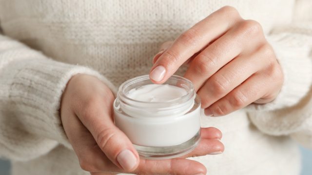 Woman holding jar of moisturizing cream, closeup. Winter cosmetic. Space for text