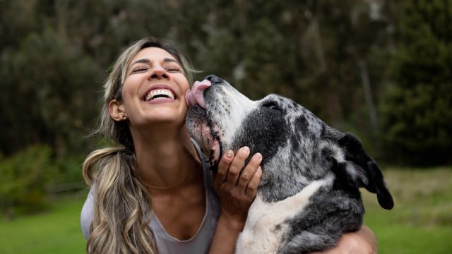 Happy woman playing with her dog outdoors
