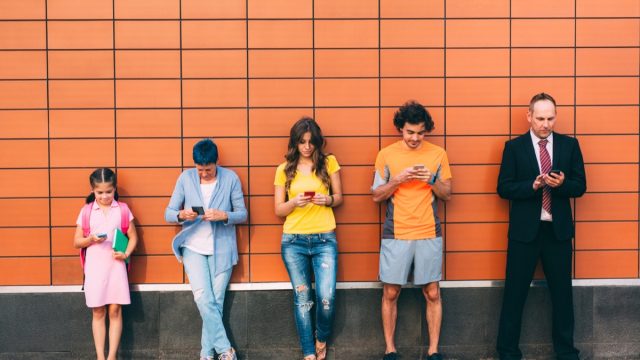 different generations lined up against a wall, texting