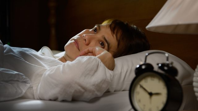 Woman with insomnia lying in bed with open eyes