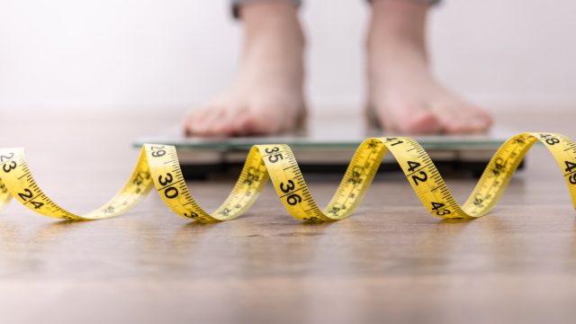 woman on scale with measuring tape