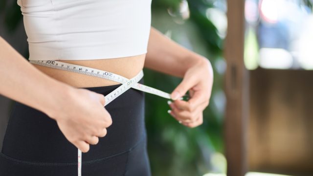 woman measuring herself for weight loss