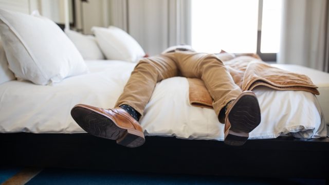 man relaxing on hotel bed with only his legs and feet showing