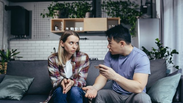 Couple arguing and fighting on couch about credit card bill or finances