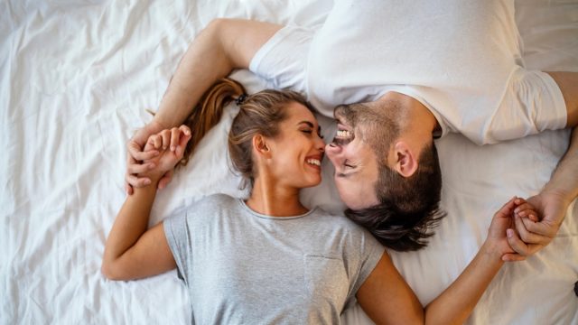 man and woman embracing in bed after waking up