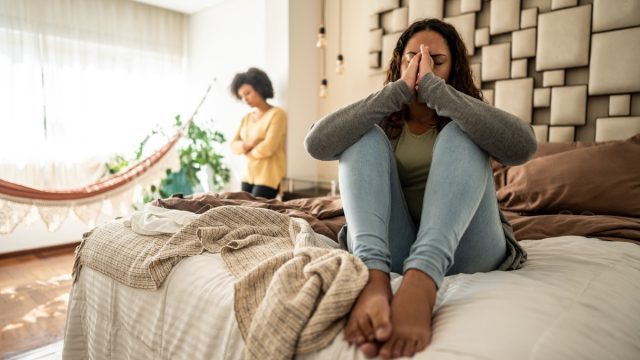 Emotional Person on Bed with Detached Person By Window