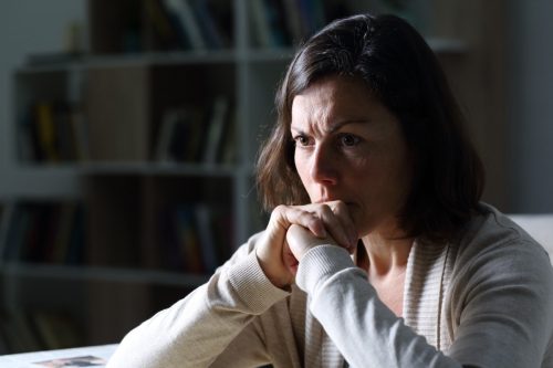 Woman sitting with her chin in her hands looking upset